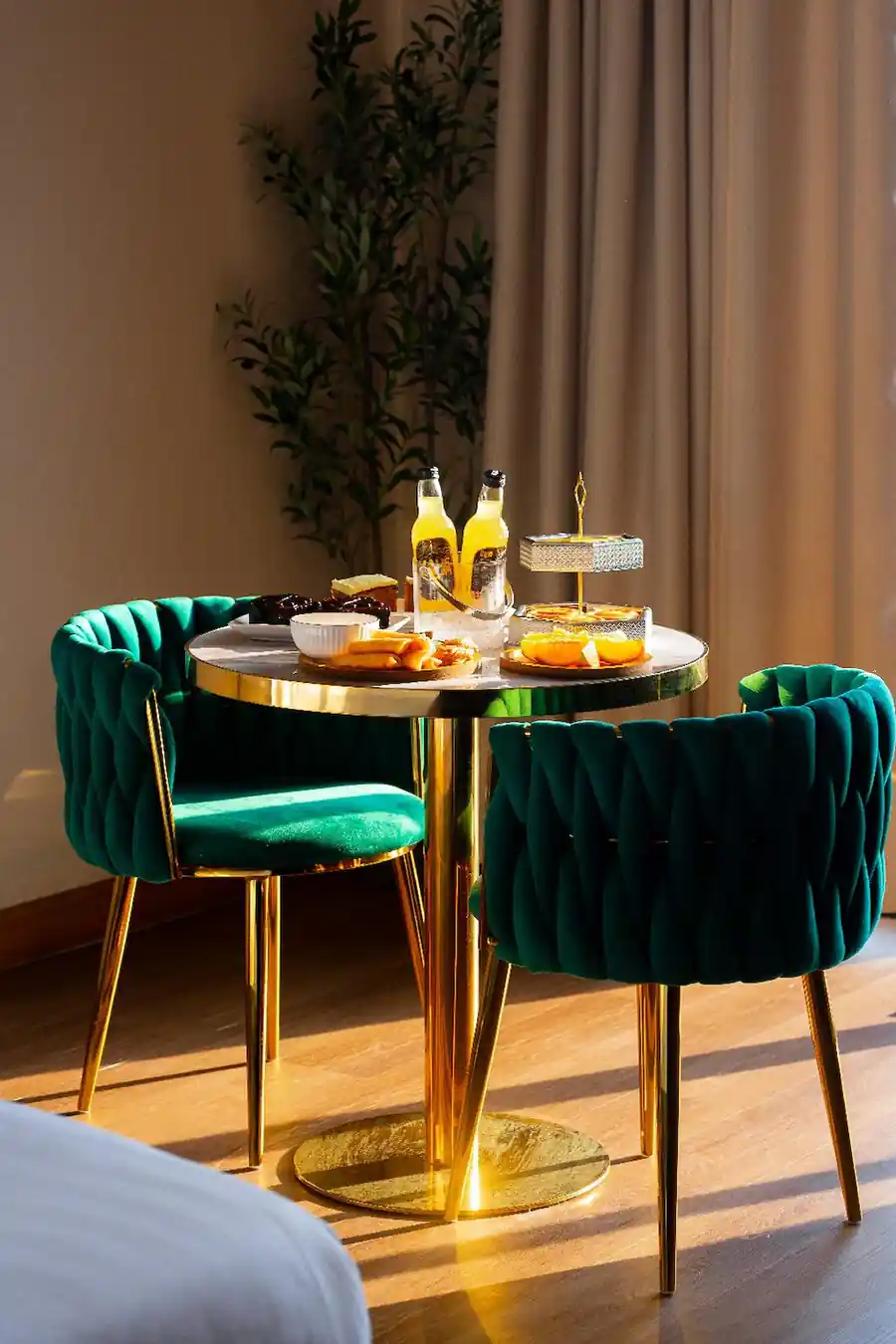 Elegant snack and drink setup on a marble table with teal velvet chairs inside the Deluxe Suite at Turtle Seaweed Resort.